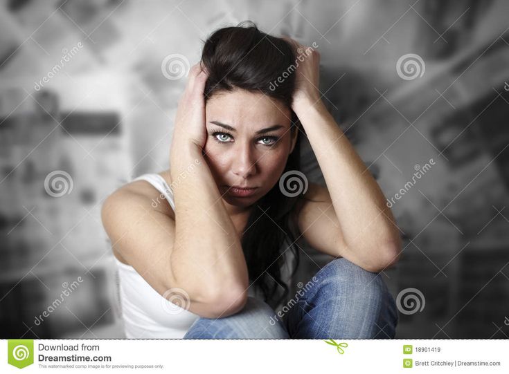 a woman sitting on the floor with her hands behind her head and looking at the camera