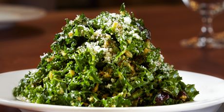 a white bowl filled with greens on top of a table