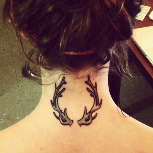 a woman with a tattoo on her neck has birds in the shape of antlers