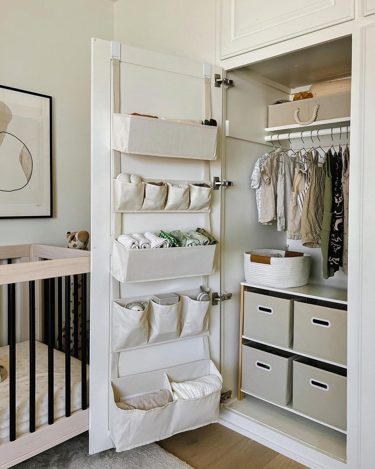 a baby's nursery closet with clothes hanging on the wall and storage bins