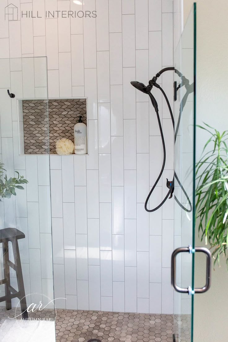 the shower door is open to reveal a bathroom with tiled floors and walls, along with a plant