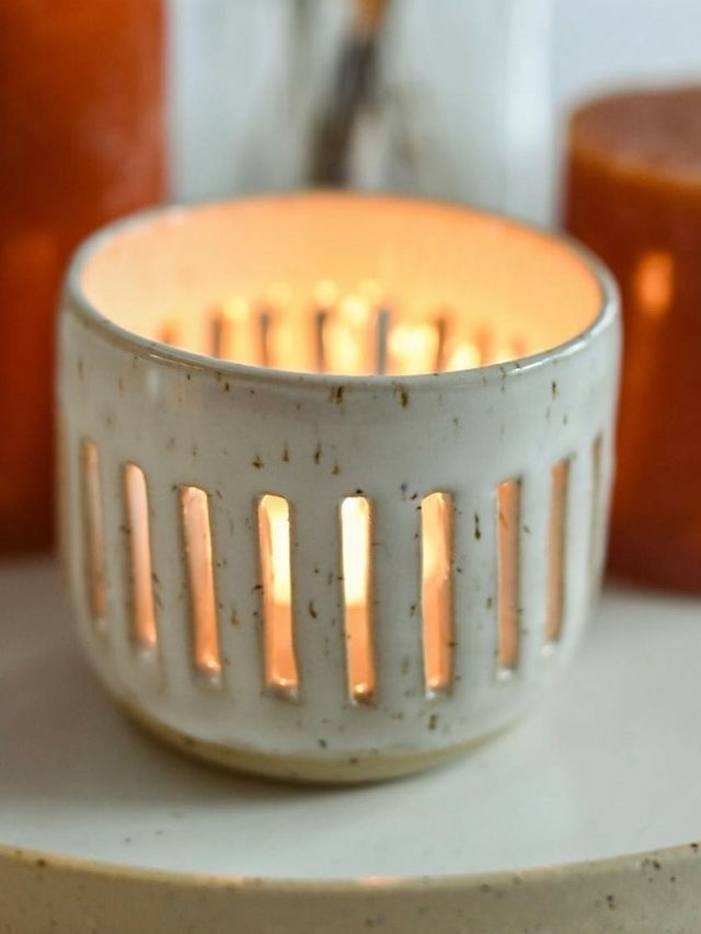 a white candle holder sitting on top of a table