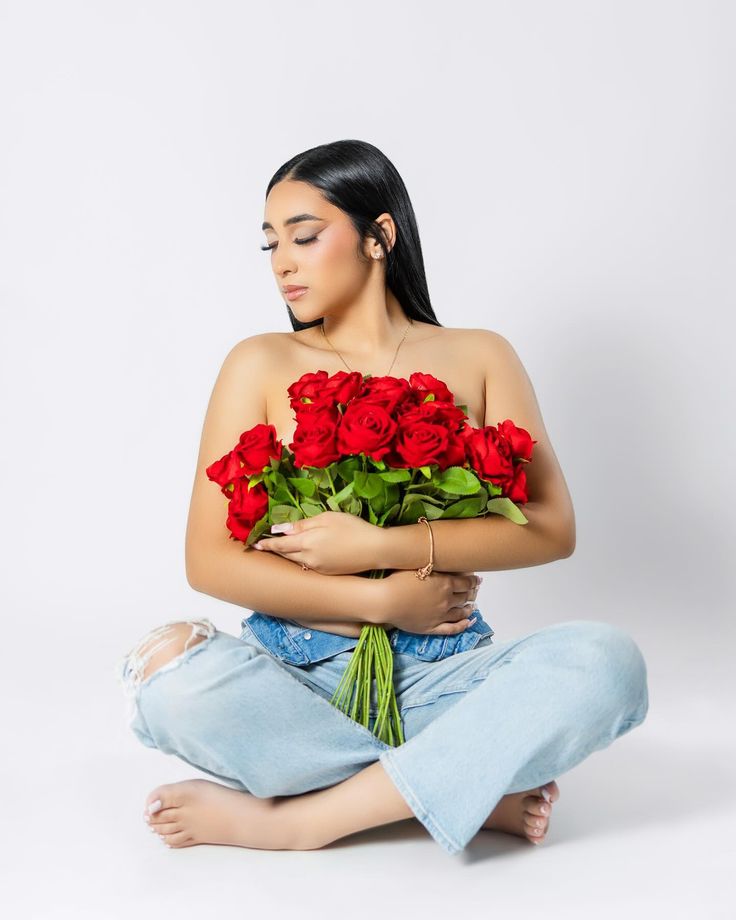 a woman sitting on the floor with roses in her lap and holding it up to her chest