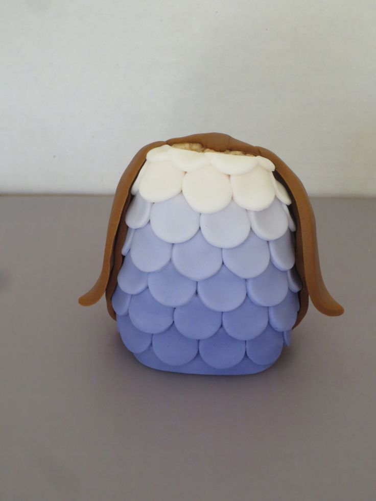 a small blue and white purse sitting on top of a gray table next to a cup