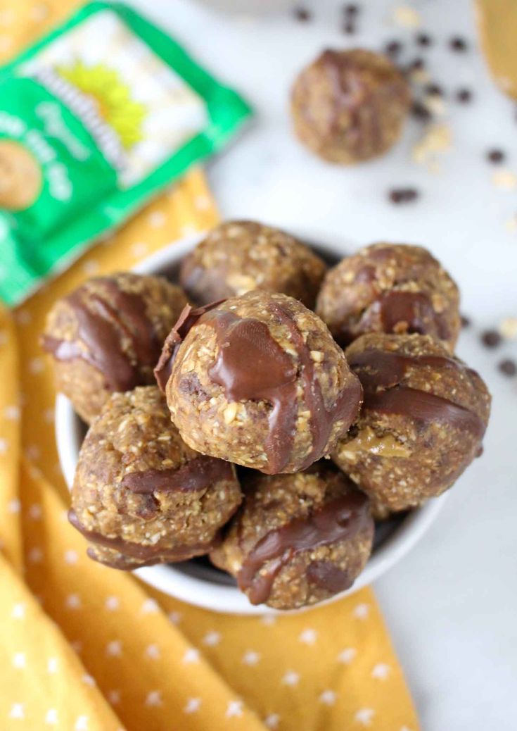 chocolate peanut butter energy bites in a white bowl on a yellow and white tablecloth