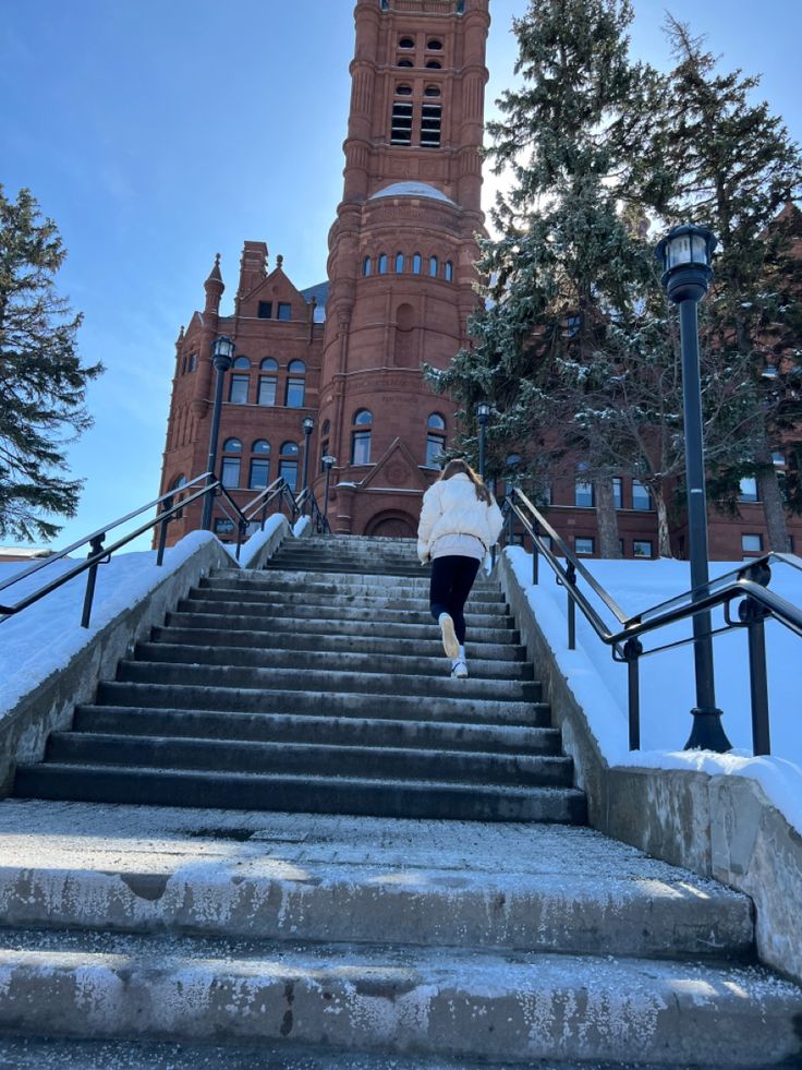 a person walking up some steps in front of a building with a clock tower on top