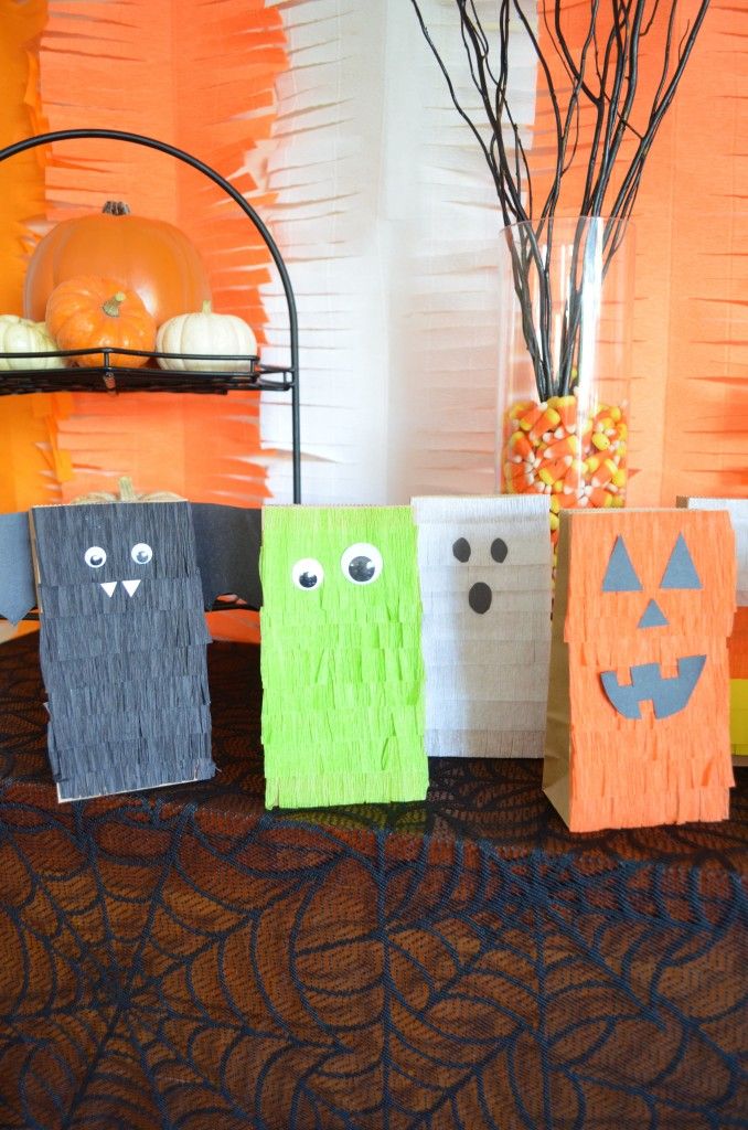 halloween treat bags are lined up on a table in front of an orange wall and tree