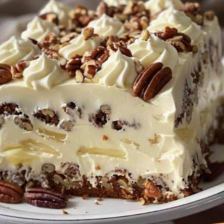 a piece of cake with white frosting and pecans on top is sitting on a plate