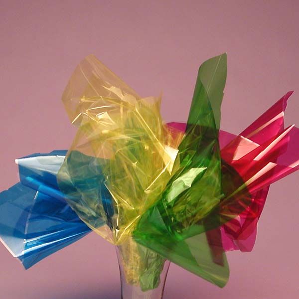 colorful plastic bags in a glass vase on a pink background