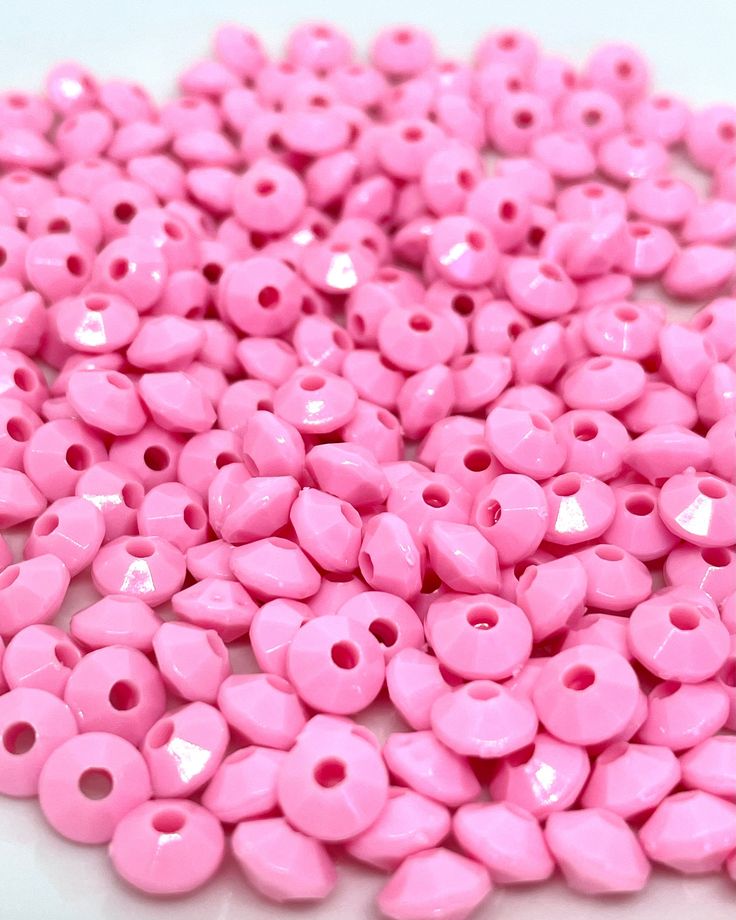 pink plastic beads on a white surface