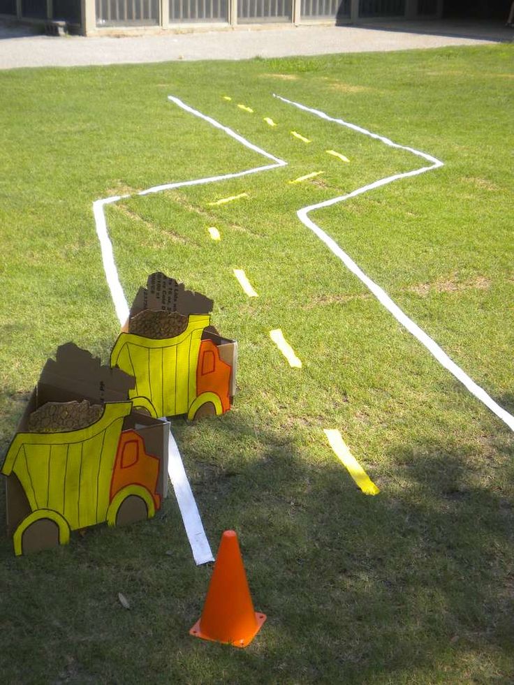 some cones are sitting in the grass near an obstacle course that is painted yellow and orange