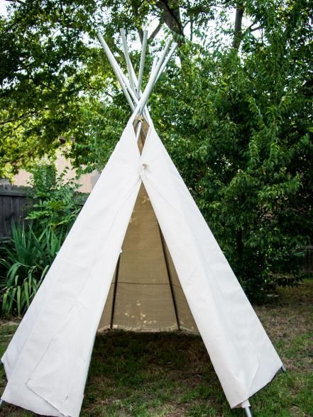 a teepee sitting in the grass near some trees