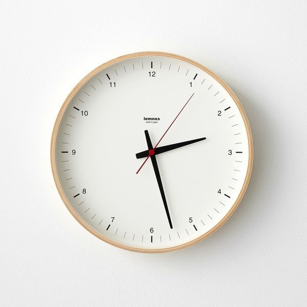 a white clock with red hands and black numbers on the face against a white background