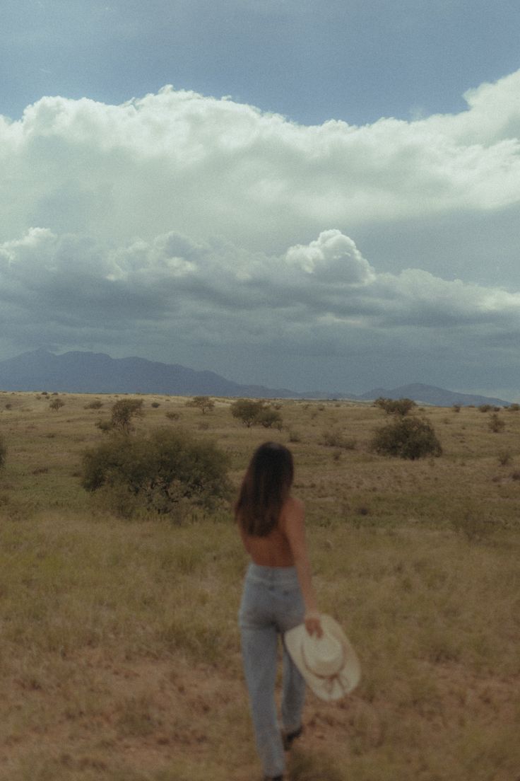 a woman holding a white frisbee on top of a dry grass covered field