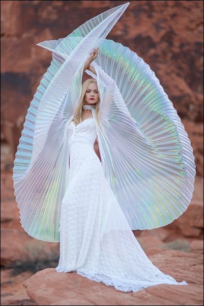 a woman in a white dress is holding an angel's wings over her head