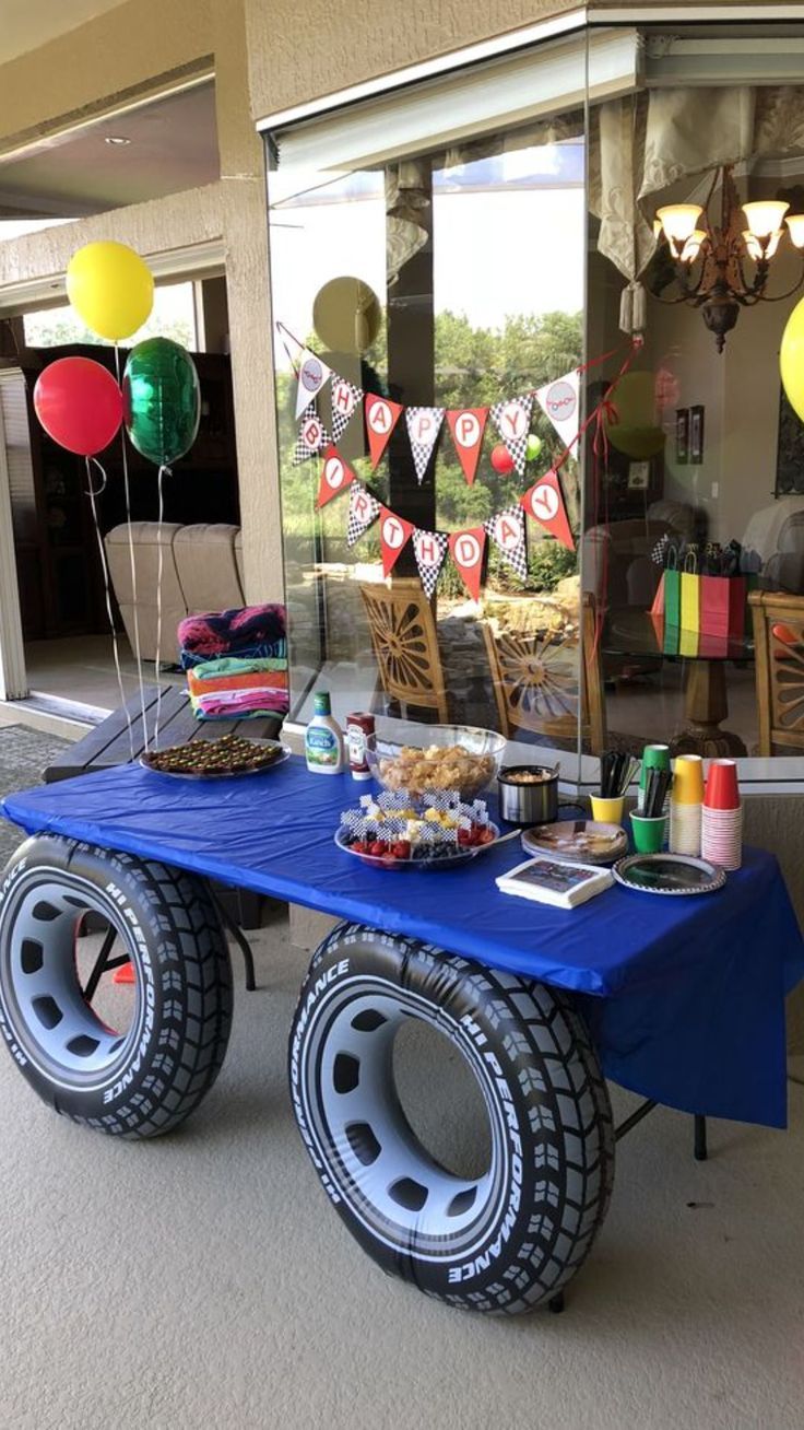 a blue table topped with lots of balloons and food on top of it's wheels