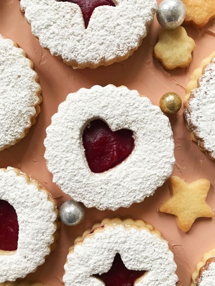 some cookies and pastries are arranged on a pink surface with silver ornaments around them