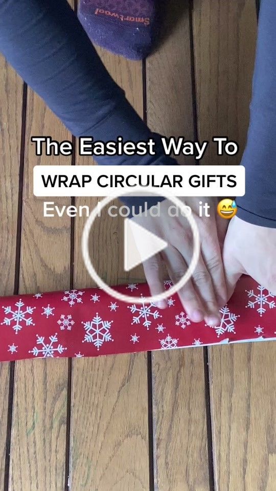 a person wrapping a red and white christmas present with the text, the fastest way to wrap circular gifts ever could it?