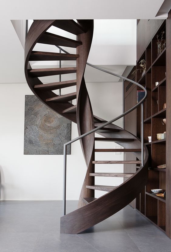 there is a spiral staircase in the living room with bookshelves on either side