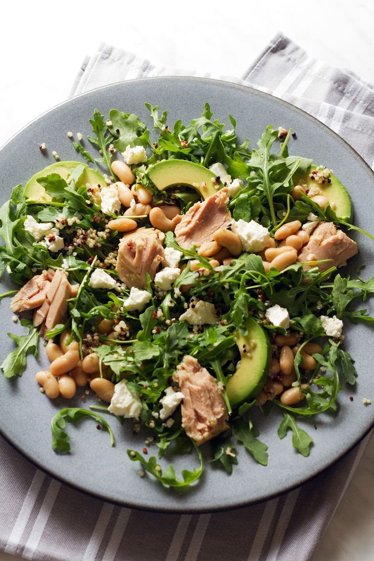 a salad with tuna, avocado and feta cheese on a blue plate