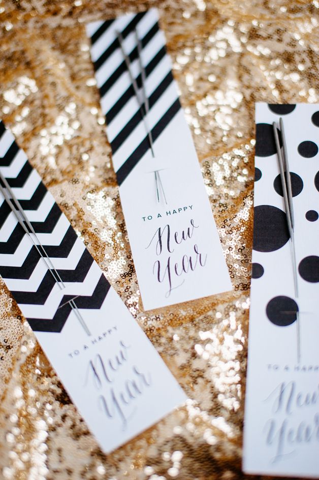 three black and white striped tags on a gold sequin table cloth with polka dots