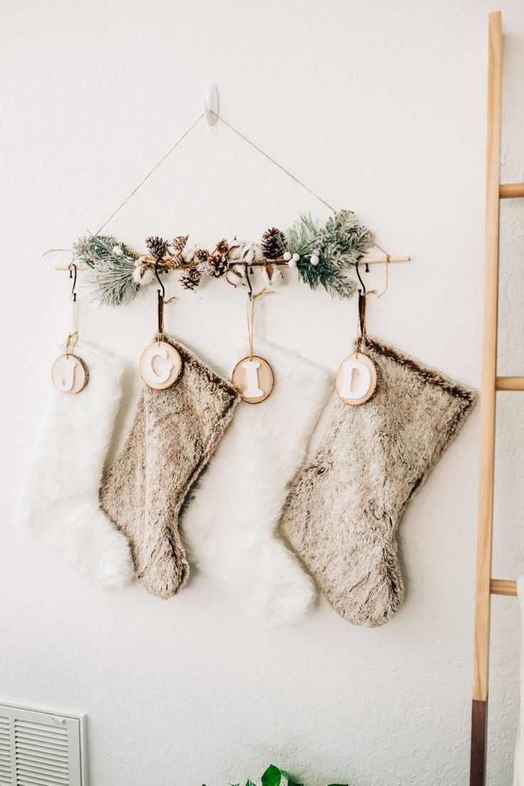 two christmas stockings hanging on a wall with pine cones and greenery next to them