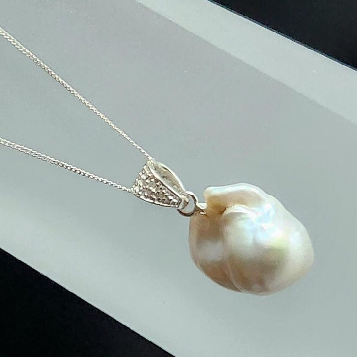 Stunning Freshwater Cultured Baroque Pearl with a 925 Sterling Silver bail Pave set with six 1mm  Round Diamonds 0.04cts on a Silver chain. The Pearl has been bleached to enhance the whiteness of the Pearls Nacre, Baroque Pearls make stunning standout pendants add the diamonds for a little sparkle and this pendant is sure to get compliments. The simple elegance of this Pearl Pendant will suit all skin tones and would be great for a Wedding, night out or anytime. Silver Pear-shaped Sterling Pearl Necklace, Silver Pear-shaped Sterling Silver Pearl Necklace, Sterling Silver Pear-shaped Pearl Necklace, Exquisite White Jewelry With Pearl Charm, Pear-shaped White Gold Sterling Silver Necklace, Timeless White Teardrop Jewelry, White Gold Drop Jewelry With Pearl Charm, White Gold Pendant Necklace With High Luster, White Pearl Charm Drop Jewelry