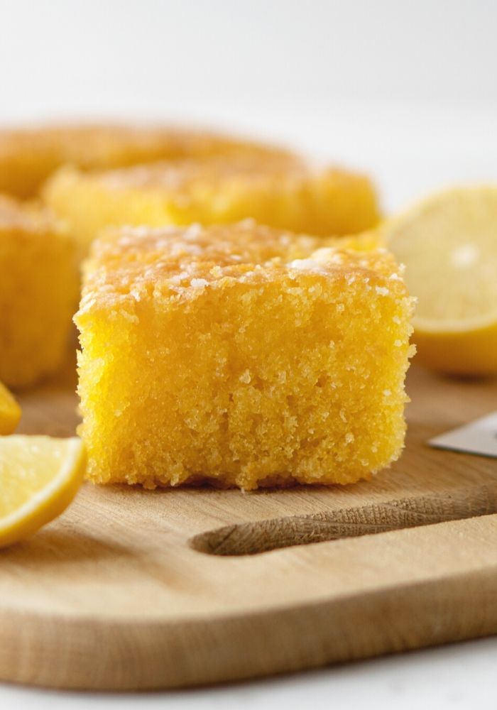 a wooden cutting board topped with slices of lemon cake