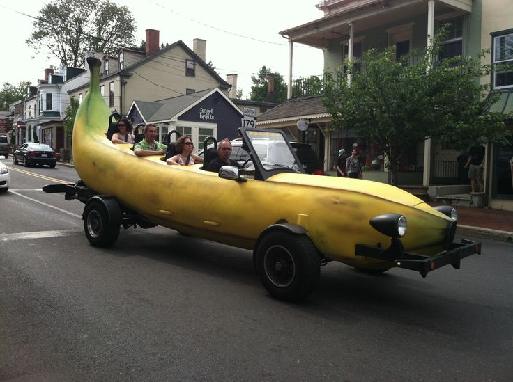 people are riding in the back of a banana shaped car on a street with other cars