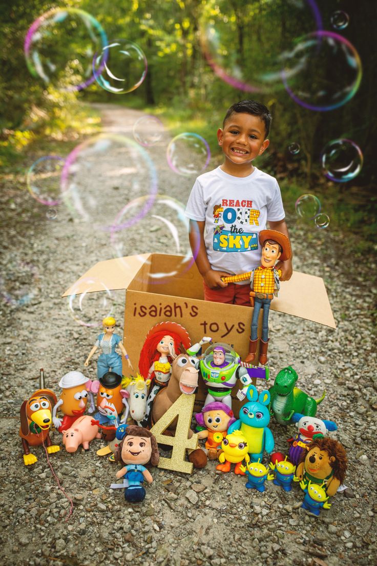 a young boy standing in front of a cardboard box filled with toy figures and bubbles