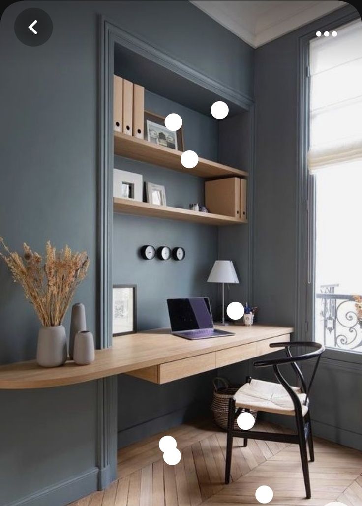 a desk with a laptop computer on top of it next to a lamp and bookshelf