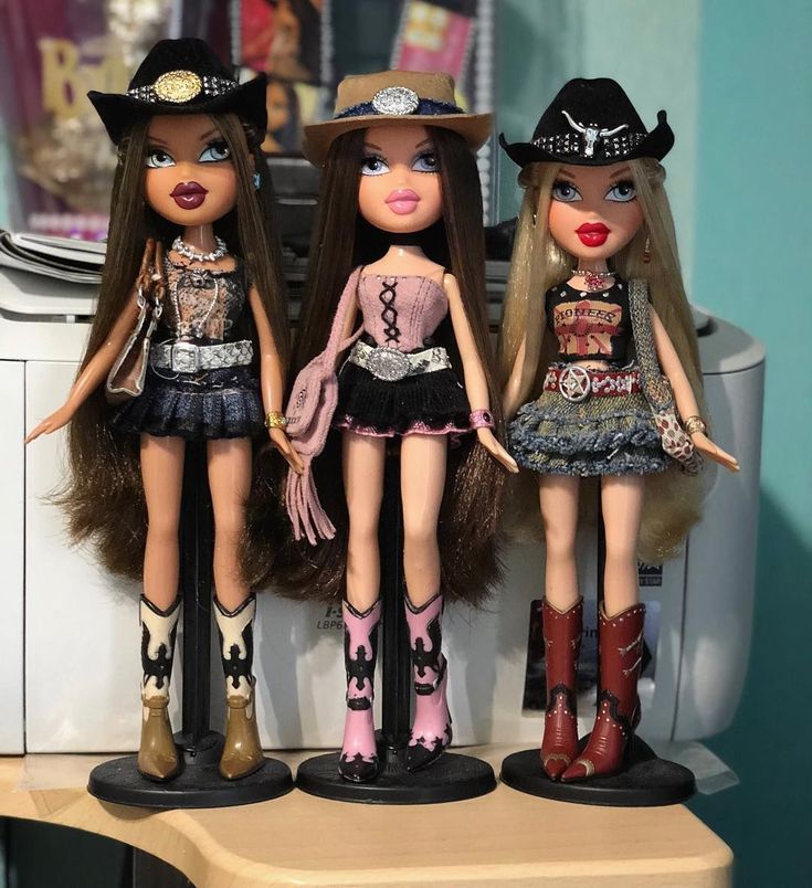 three dolls with hats and boots are standing next to each other on a table in front of a mirror