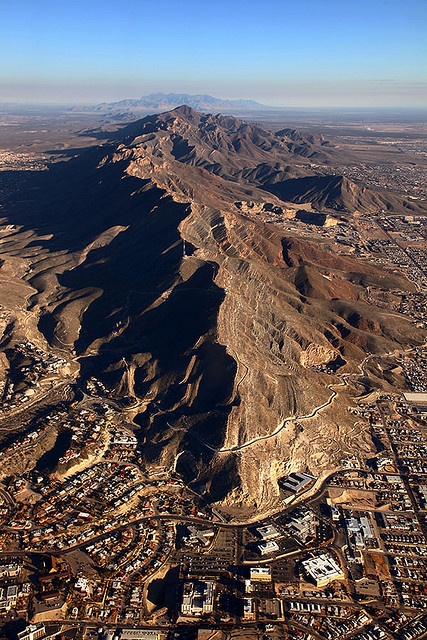 an aerial view of a city in the desert with mountains and buildings on either side