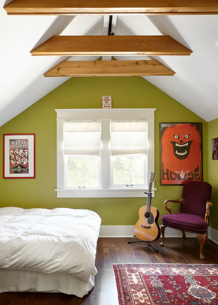 a bedroom with green walls, white bedding and an orange guitar on the floor