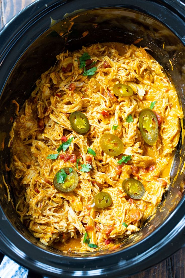 a crock pot filled with shredded cheese and jalapenos