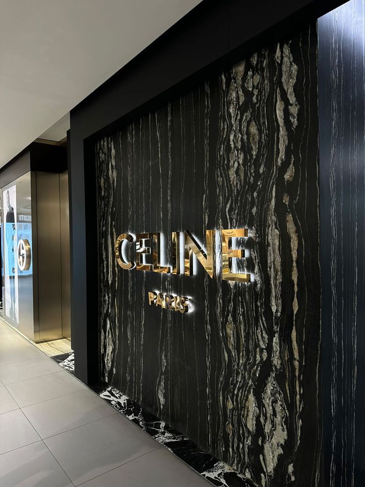 an entrance to a building with black marble and gold lettering on the front wall, along with white tile flooring