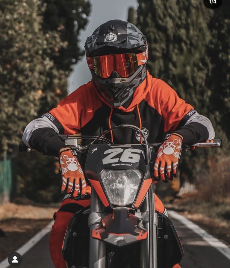 a man riding on the back of a motorcycle down a road with trees in the background