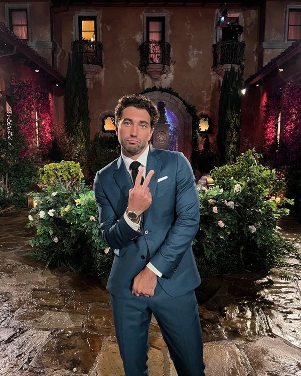 a man in a blue suit and tie posing for a photo with his hand up