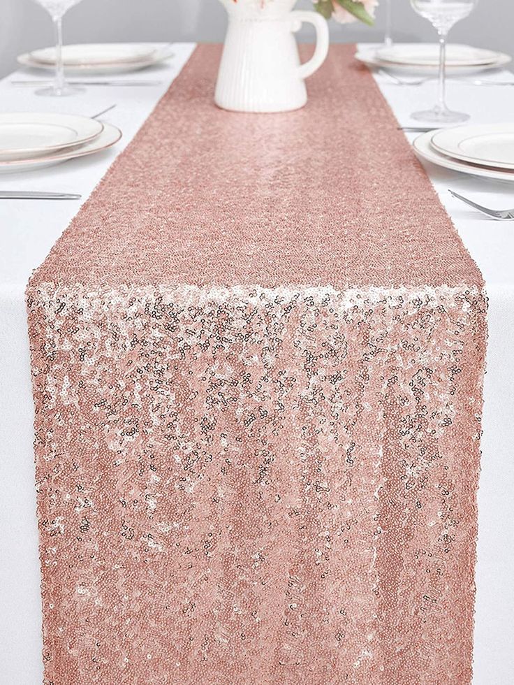 the table is set with white plates and pink flowers in a vase on top of it