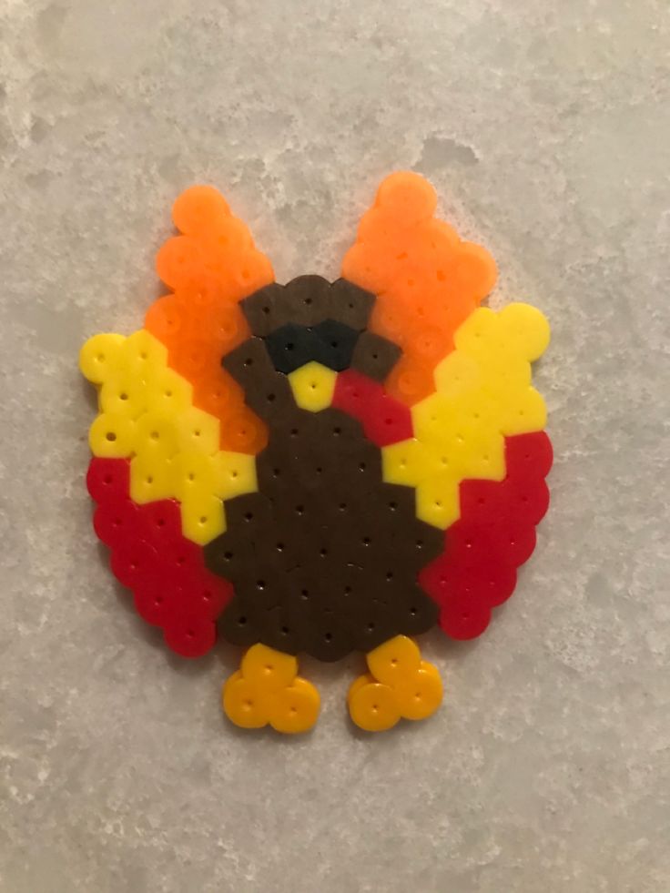 a turkey shaped brooch sitting on top of a white surface with holes in it