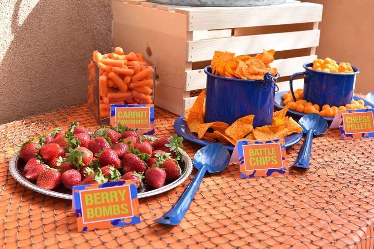 a table topped with lots of different types of foods and snacks next to blue buckets filled with strawberries