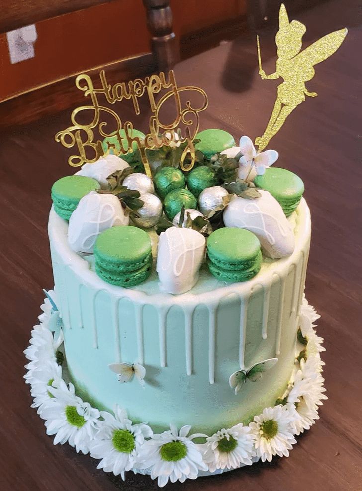 a birthday cake decorated with green and white frosting, topped with macaroons