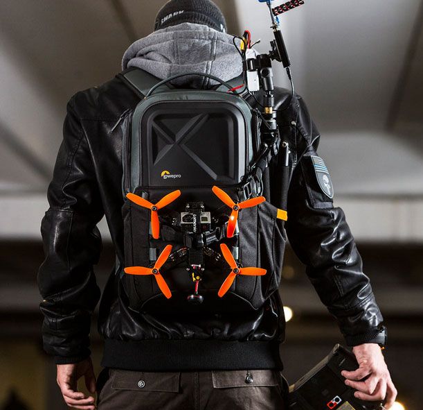 a man wearing a black jacket with an orange and grey back pack on his back