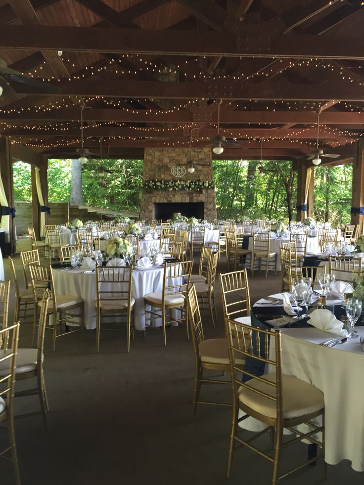 tables and chairs are set up for a formal function in the gazebo with lights strung from the ceiling