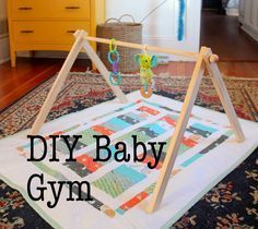 a baby's play mat with a wooden frame and toy rings hanging from it