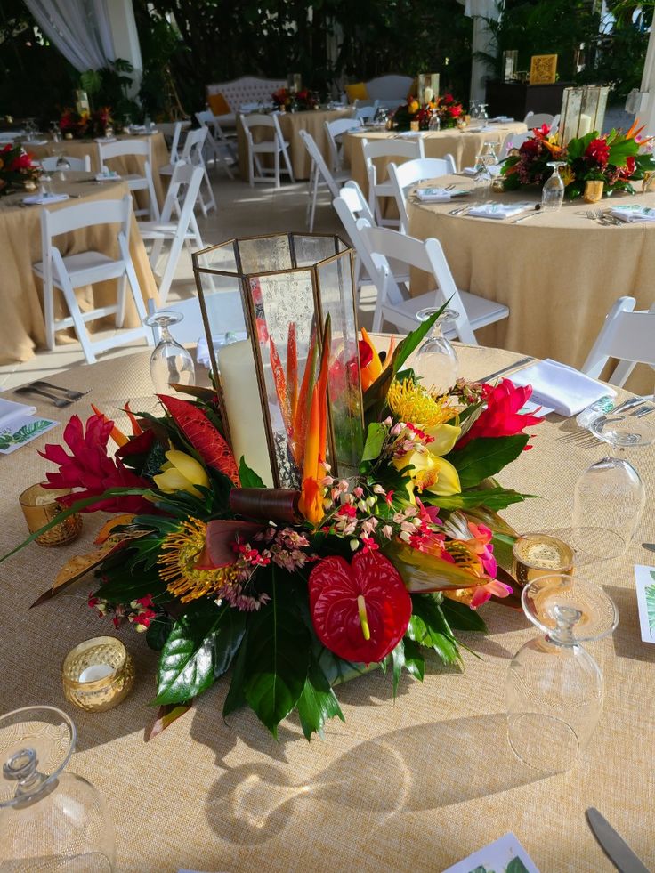 an arrangement of flowers and candles on a table at a wedding or other function with place settings