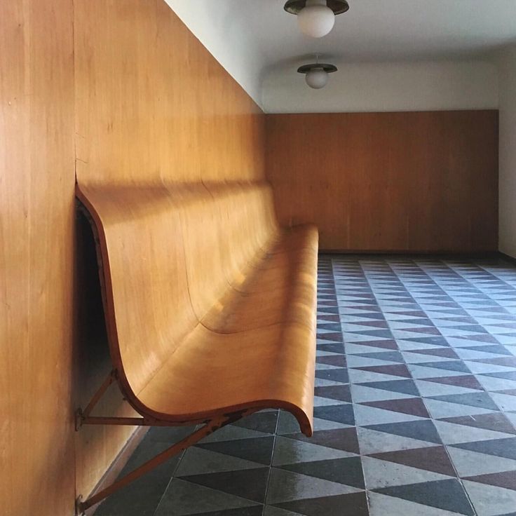 a wooden bench sitting in the corner of a room with checkered floor and walls