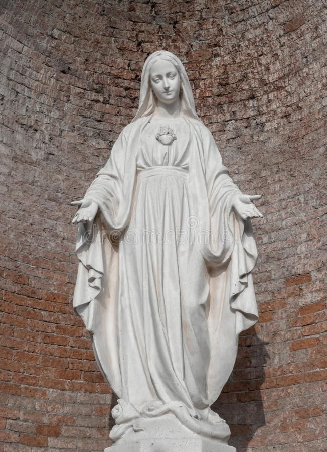 a statue of the virgin mary in front of a brick wall