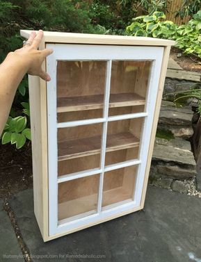 a person is holding up a bookcase made from an old window pane and some wood