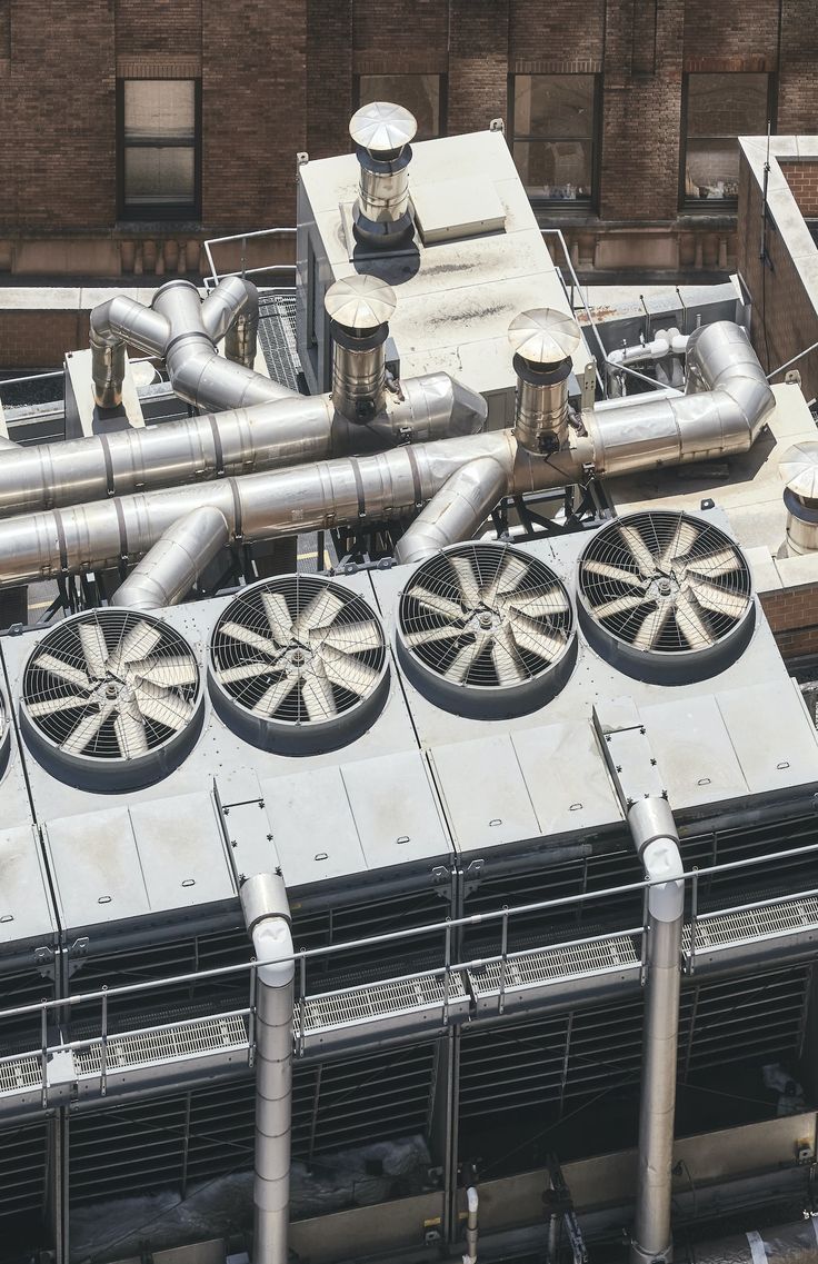 an overhead view of pipes and air conditioners on the roof of a large building